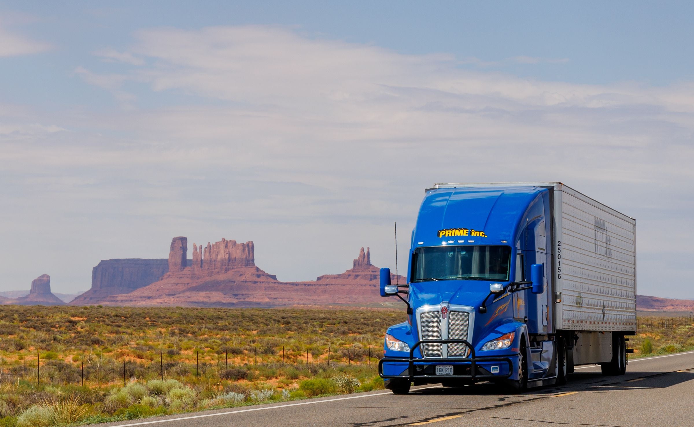 Semi truck on open highway through Monument Valley — Sacred Road Supply hero
